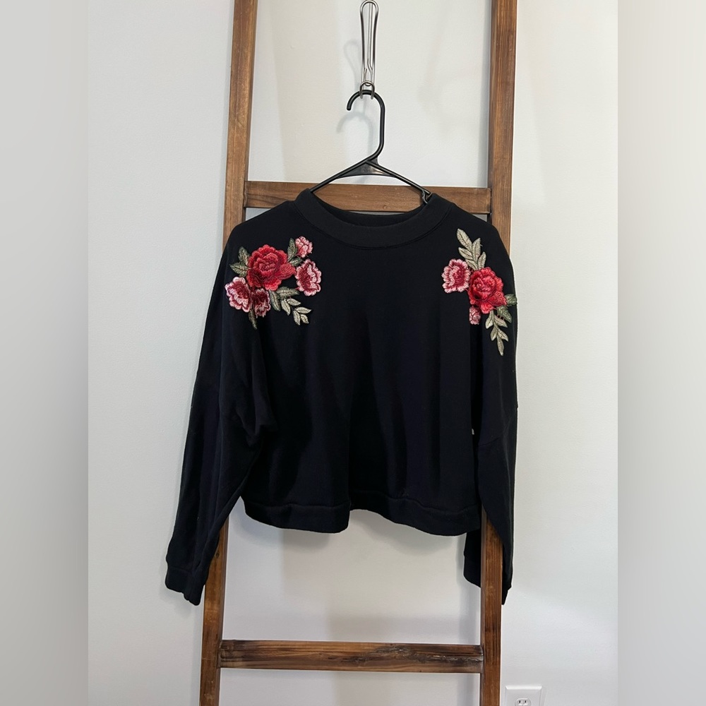 Black cropped sweater with flower embroidered detail.